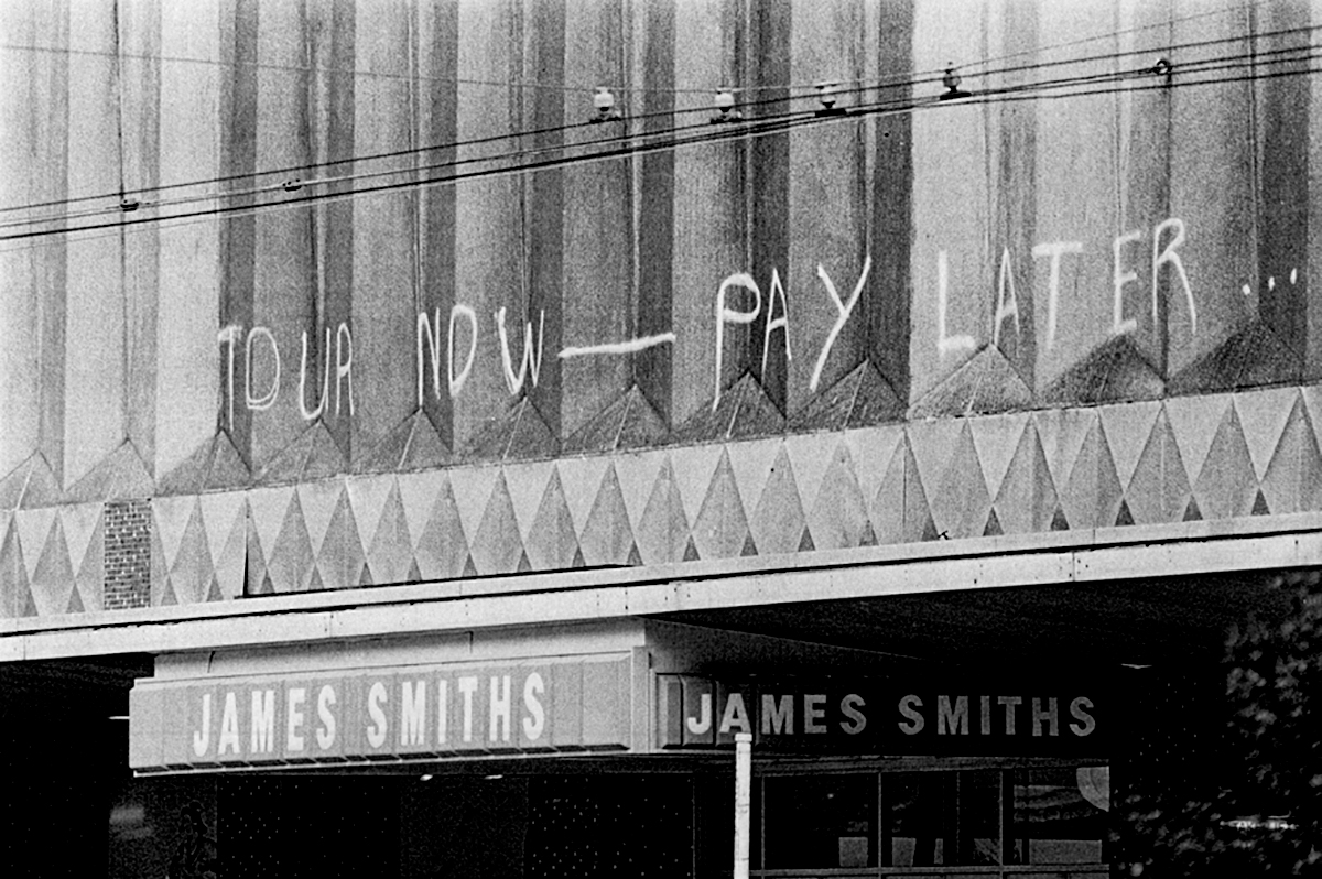 Anti Springbok rugby tour graffiti “Tour now—pay later”, spray painted on the front of Challenge House, premises of James Smith’s, Lambton Quay, Wellington. ca. 26 August 1981